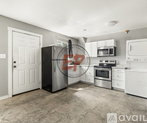 A kitchen with a black fridge, white cabinets, and a white door.