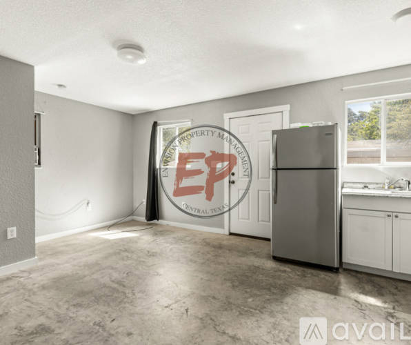 A kitchen area with a refrigerator, cabinets, and a window.