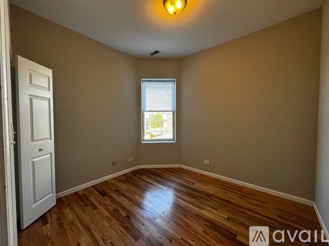 A room with wooden flooring and a window with blinds.