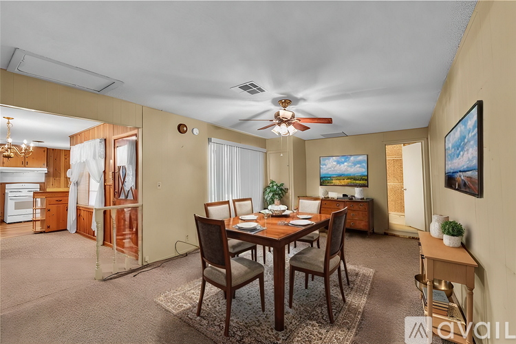 A dining room with a table set for four and a ceiling fan.