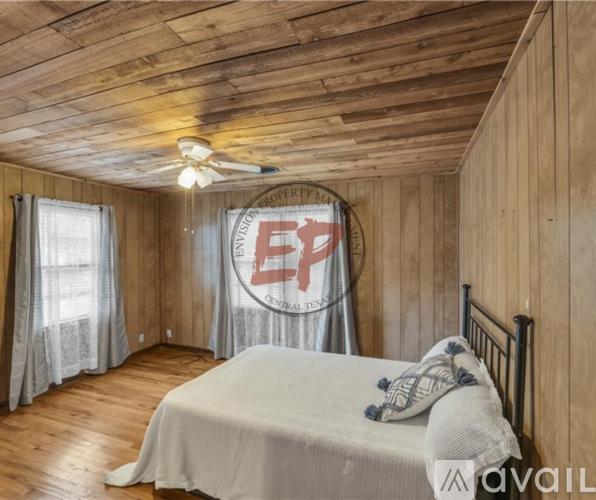 A bedroom with wooden walls and a bed with a white comforter.