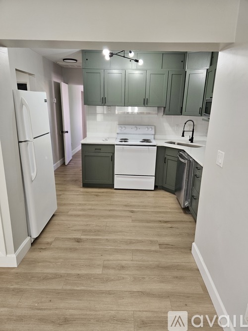 A kitchen with white appliances and green cabinets.