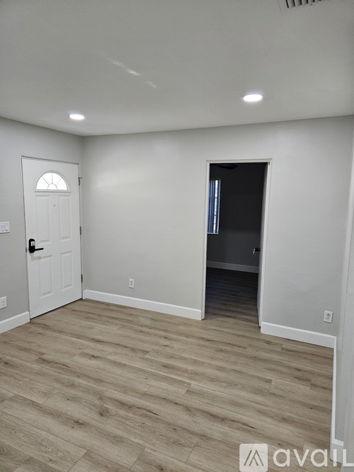 A room with a white door and a wooden floor.