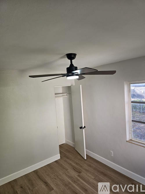 A room with a ceiling fan and a door leading to another room.