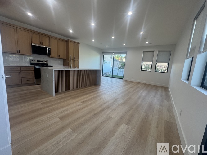 A spacious kitchen with wooden floors and cabinets.