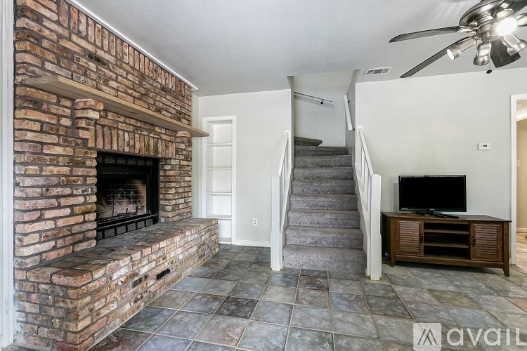 A living room with a brick fireplace and a staircase.