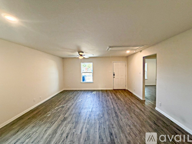 A spacious room with wooden flooring and white walls.