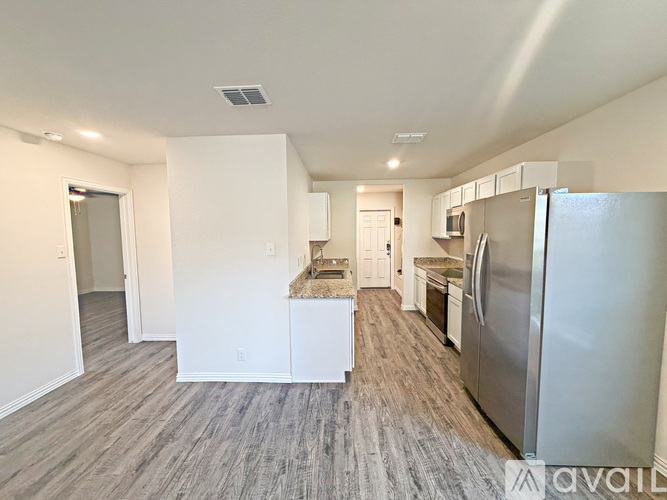 A kitchen with a refrigerator, sink, and cabinets.