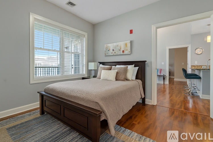 A bedroom with a large bed and a window with blinds.