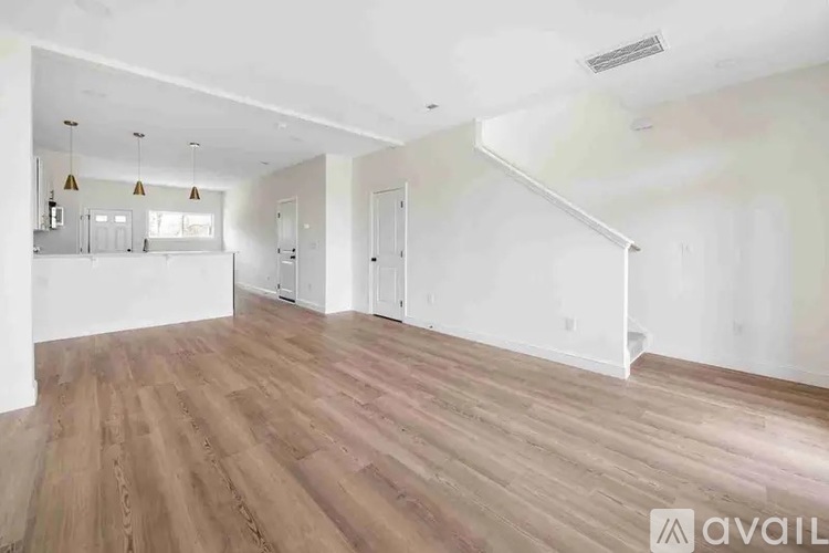 A spacious room with wooden flooring and white walls.
