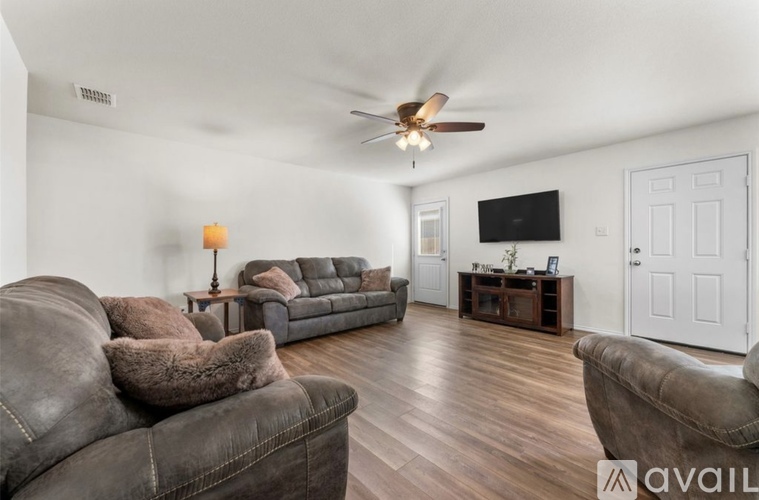 A living room with a brown leather couch and a flat screen TV mounted on the wall.