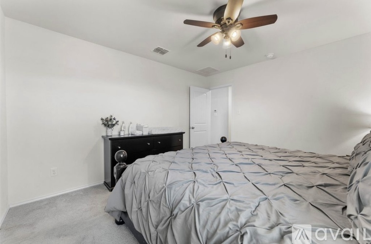 A bedroom with a bed, dresser, and ceiling fan.