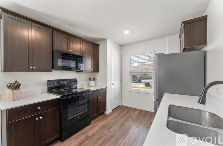 A kitchen with dark wood cabinets and black appliances.