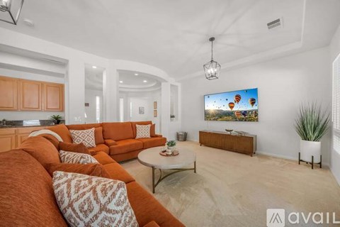 A living room with orange couches and a television displaying a hot air balloon scene.