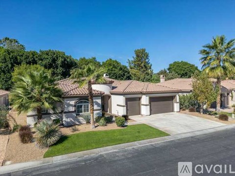 A house with a driveway and palm trees in front.