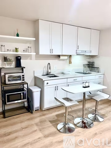A kitchen with white cabinets and a white island with a bar stool.