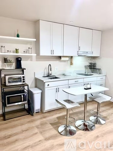 A kitchen with white cabinets and a white island with a bar stool.