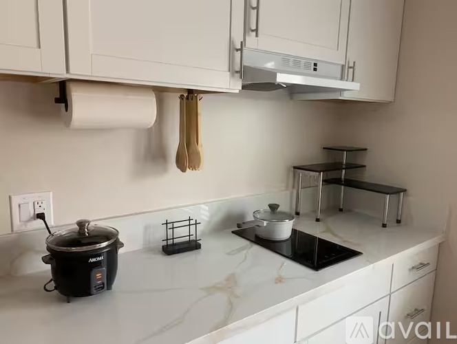 A kitchen with a black rice cooker on the counter.
