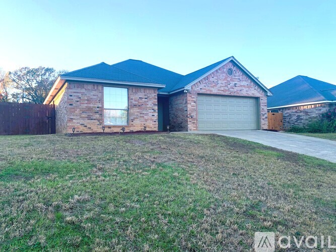 A house with a garage is situated in a grassy area.