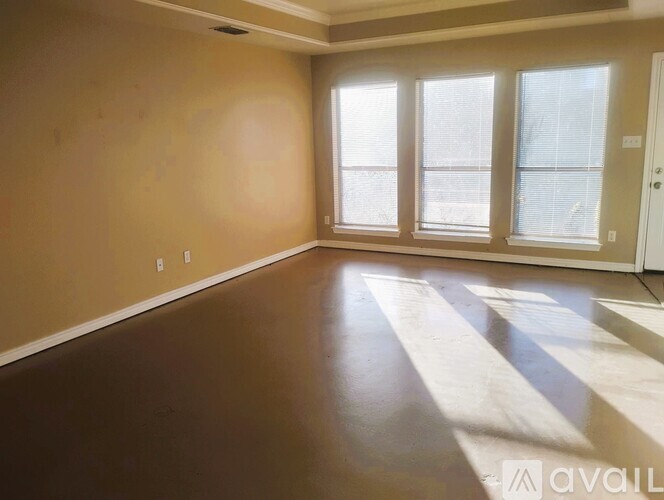 A room with brown flooring and a large window.