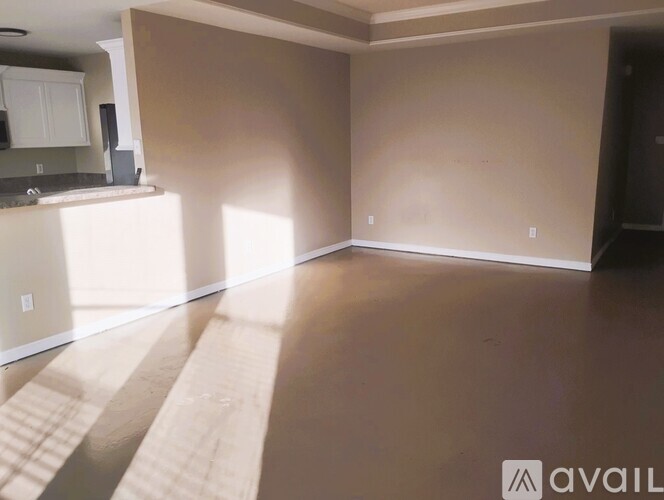 A spacious living room with a kitchen area in the background.
