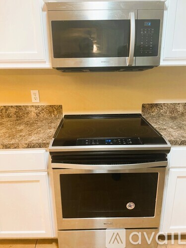 A stainless steel microwave oven is mounted above a stove in a kitchen.
