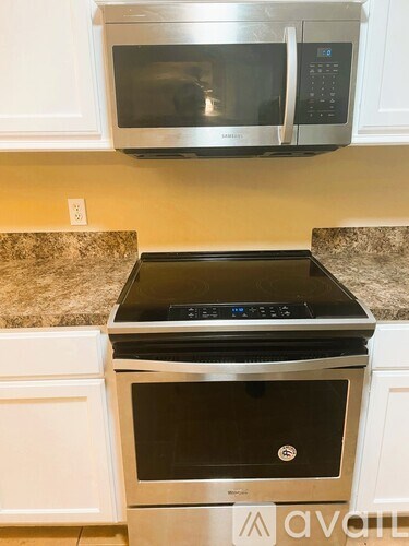 A stainless steel microwave oven is mounted above a stove in a kitchen.
