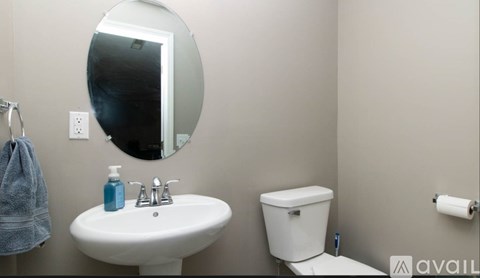 A bathroom with a toilet, sink, mirror, and towel.