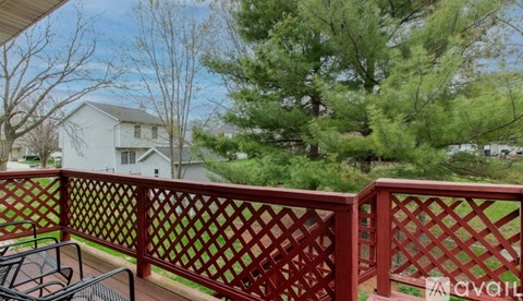 A red lattice fence on a balcony with a table and chairs.