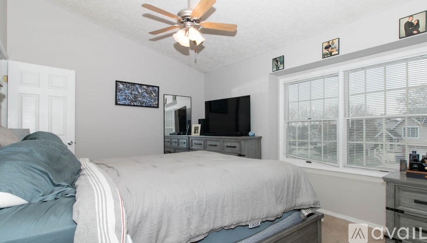 A bedroom with a bed, dresser, and a ceiling fan.