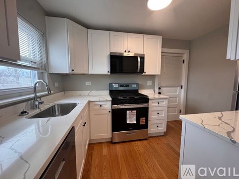 A kitchen with white cabinets and a black microwave above the stove.