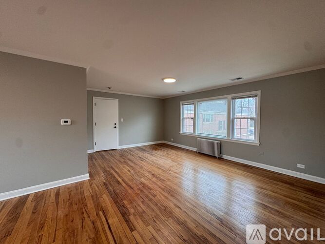 A room with wooden floors and a window with a view of a building outside.