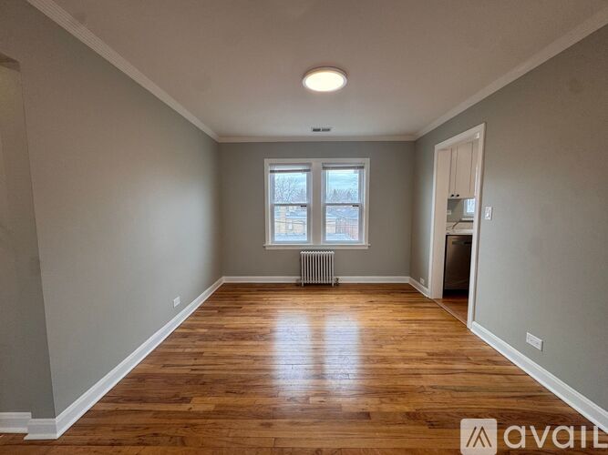 A room with wooden floors and a window with a view of a street.