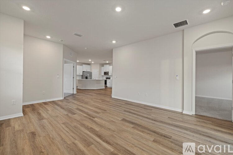 A spacious room with wooden flooring and white walls.