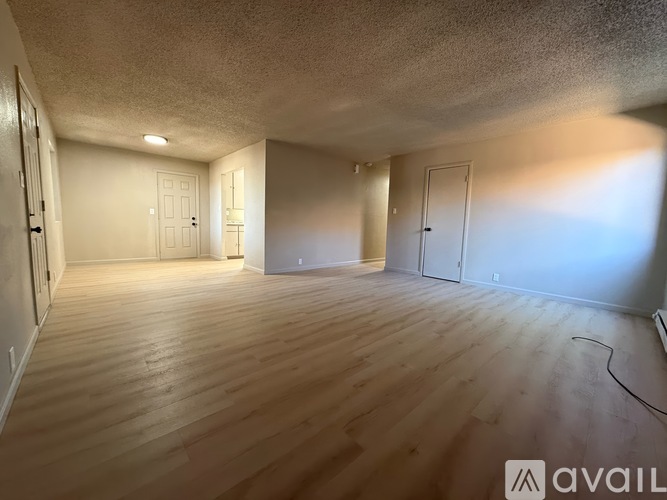 A spacious room with wooden flooring and white walls.