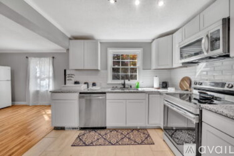 A kitchen with white cabinets and a wooden floor.