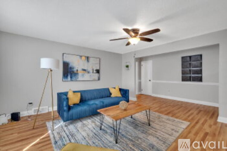 A living room with a blue couch and a ceiling fan.