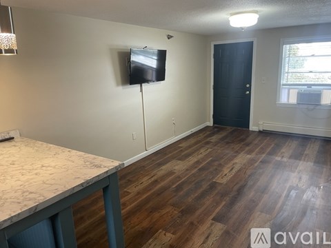 A room with a wooden floor and a flat screen TV mounted on the wall.