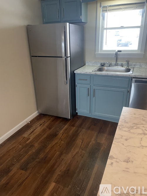 A kitchen with a refrigerator, sink, and cabinets.