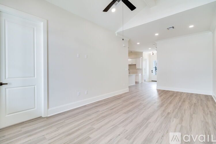 A spacious room with wooden flooring and a ceiling fan.