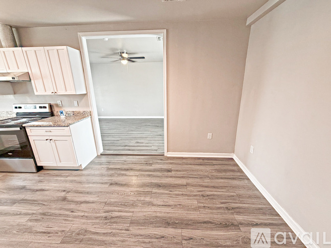 A kitchen with a white stove top oven and white cabinets.