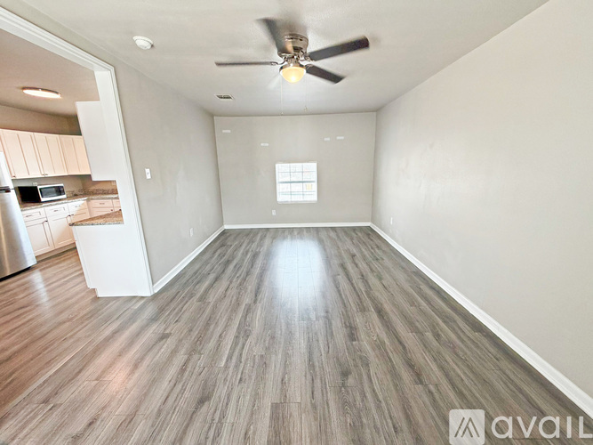 A spacious room with a ceiling fan and wooden flooring.