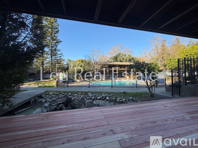 A wooden deck overlooks a pool and a landscaped yard.