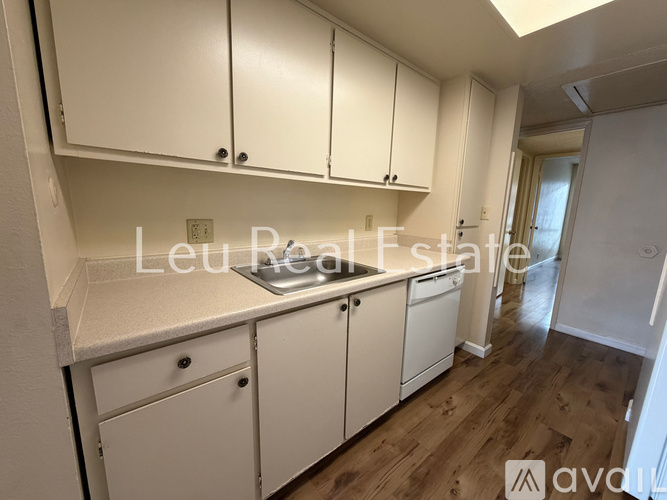 A kitchen with white cabinets and a wooden floor.