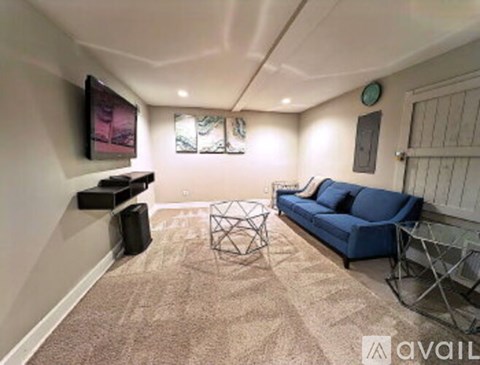 A living room with a blue sofa and a television on the wall.
