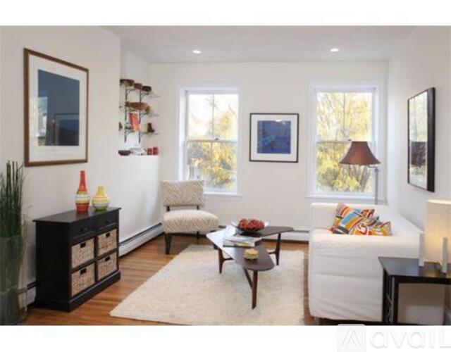 A living room with a white couch, a wooden coffee table, and a white rug.