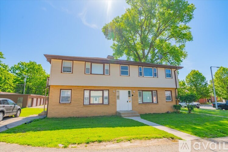 A sunny day at a two-story apartment building with a white door and windows.