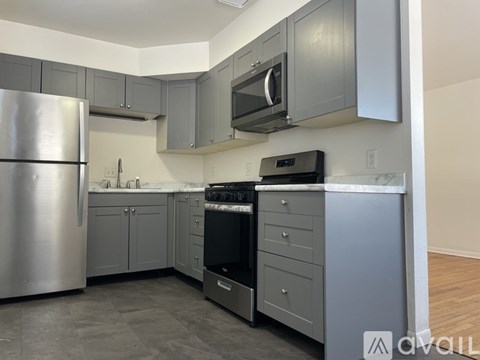 A kitchen with a stainless steel refrigerator and a black stove top oven.