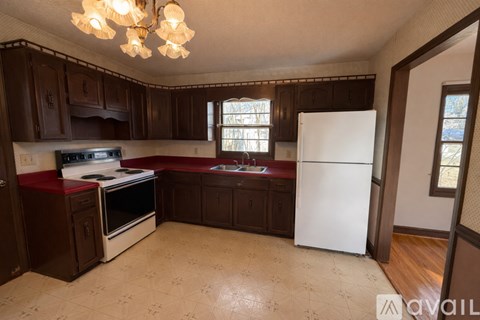 A kitchen with brown cabinets and a white refrigerator.