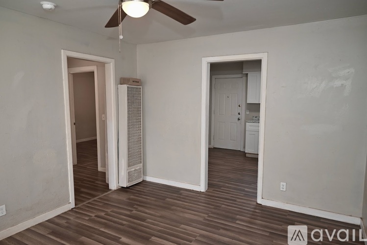 A room with a ceiling fan and wooden flooring.